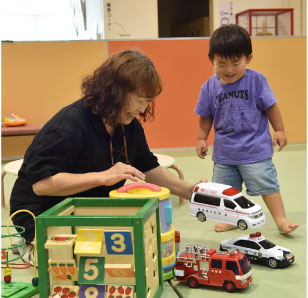 救急車のおもちゃで遊ぶ子どもと先生の写真。