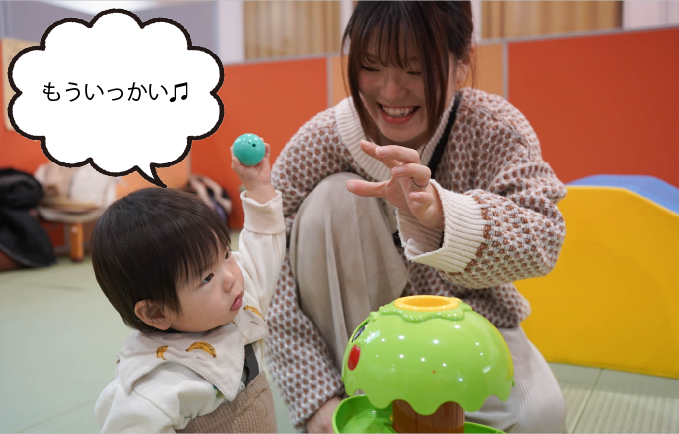 ボールのおもちゃで遊ぶ赤ちゃんとお母さんの写真。「もう一回！」
