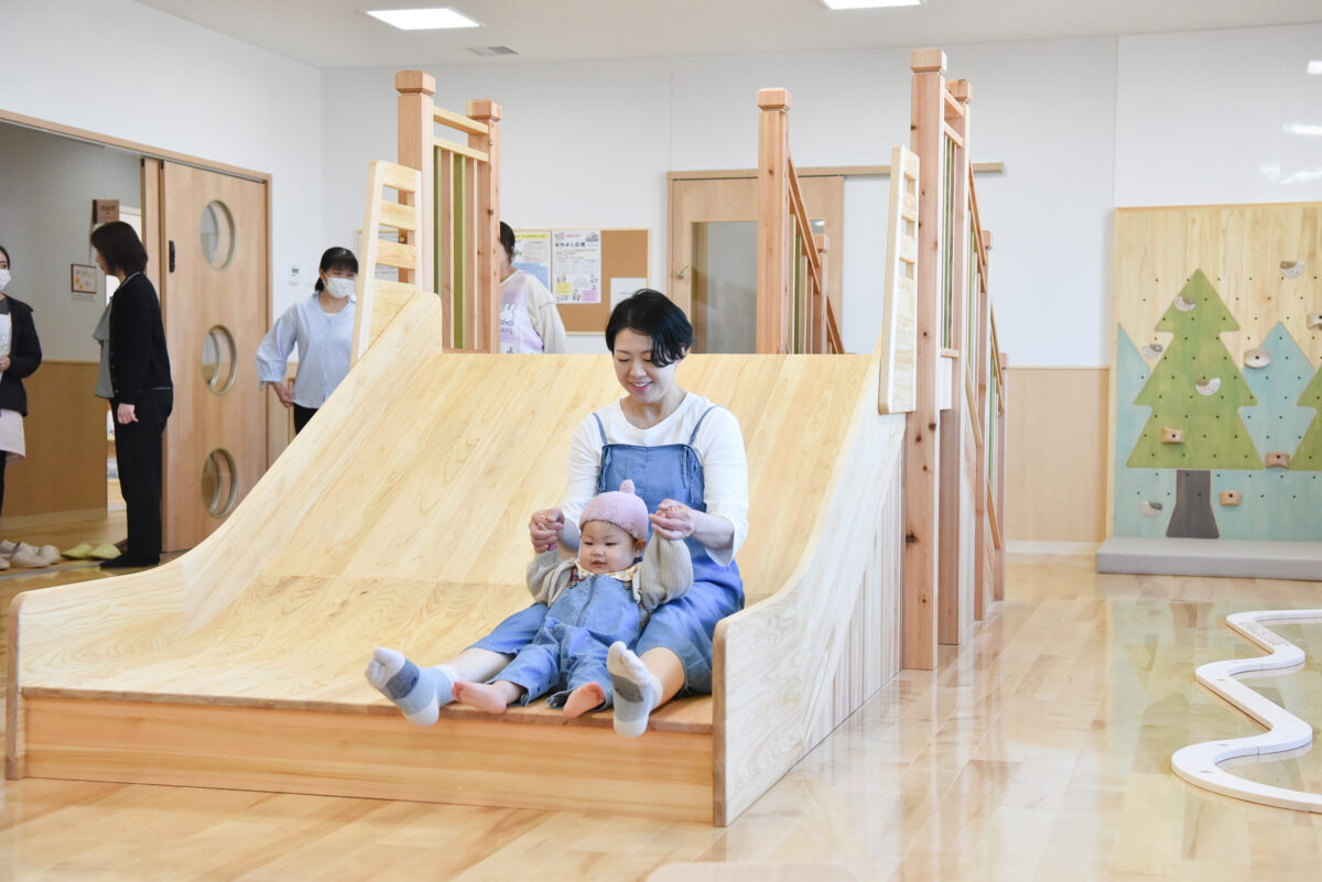 木製の滑り台で遊ぶ親子